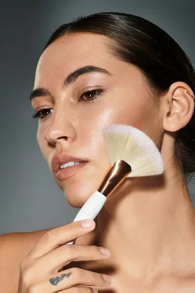 A young woman gently applies makeup, showcasing her natural beauty and glowing skin. — Stock Photo