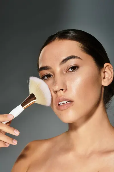 A graceful woman enhances her features with a brush, showcasing her natural beauty and confidence. — Stock Photo
