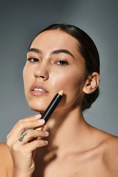 A graceful woman enhances her beauty using a makeup stick while posing confidently. — Stock Photo