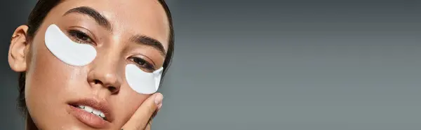 A radiant woman enhances her skincare routine with soothing under eye patches for rejuvenation. — Stock Photo