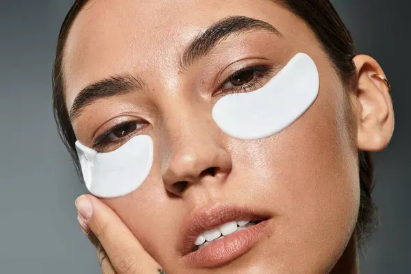 Relaxation and self care unite as a woman applies under eye patches for rejuvenation. — Stock Photo