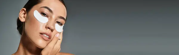 A woman applies eye patches while pampering herself in a serene evening ambiance. — Stock Photo