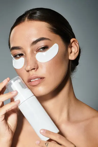 A radiant woman applies skincare near a soft backdrop while focusing on her beauty routine. — Stock Photo