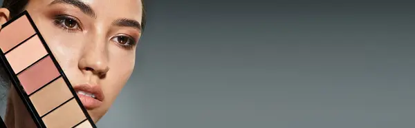 Die Frau hält eine lebendige Make-up-Palette und betont gleichzeitig ihre strahlende Schönheit und ihren Stil — Stockfoto