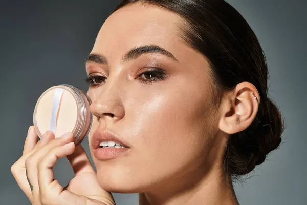 Une femme gracieuse améliore sa beauté avec le maquillage, mettant en valeur la concentration et l'élégance. — Photo de stock