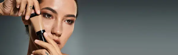 A beautiful woman focuses on perfecting her look as she applies foundation on her skin. — Stock Photo
