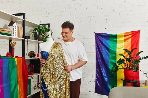 A joyful queer person admires a dazzling gown amidst bright pride decorations in a lively space. — Stock Photo