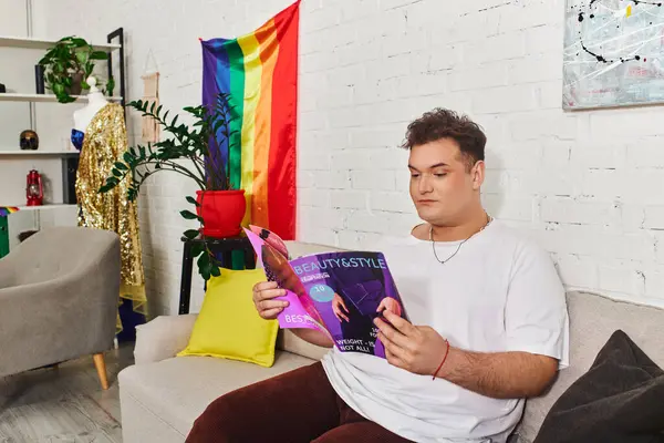 A unique individual relaxes on a sofa while engrossed in a magazine celebrating beauty and style. — Stock Photo