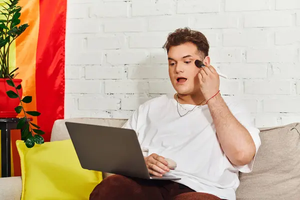 Engaged in self expression, a unique individual applies makeup on a laptop in a vibrant room. — Stock Photo