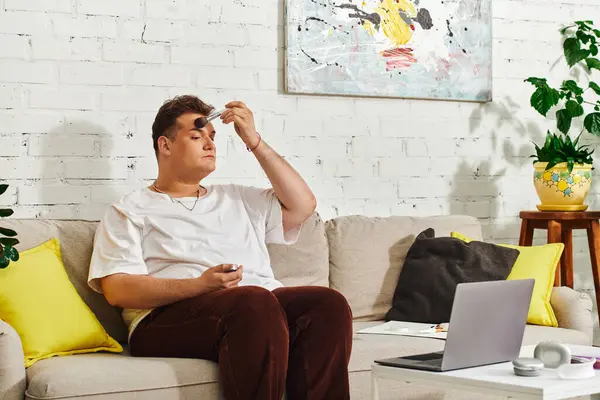 Un individu queer concentré sur le perfectionnement de leur maquillage tout en se relaxant à la maison dans un espace dynamique. — Photo de stock