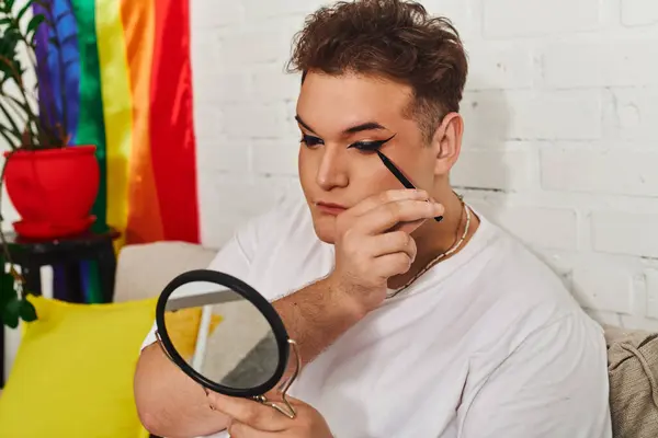 An expressive queer person enhances their look with makeup in a vibrant and welcoming room. — Stock Photo