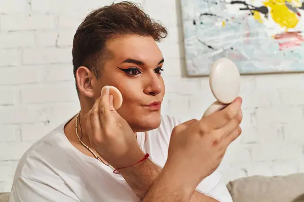 A person with unique style enhances their look using makeup and a mirror in a cozy setting. — Stock Photo
