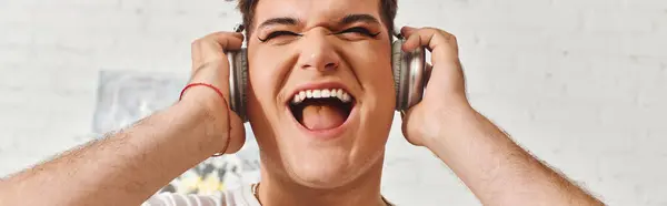 A queer person smiles, immersed in their favorite tunes with headphones on. — Stock Photo