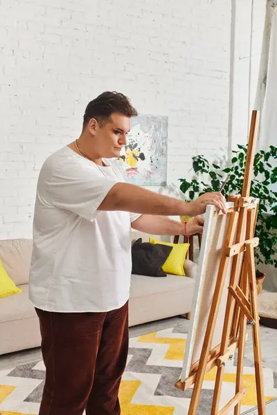 An appealing queer individual sets up a blank canvas in a lively, sunlit art studio. — Stock Photo