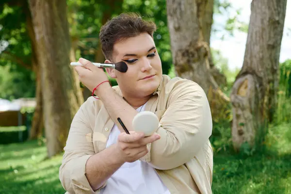 In a serene park setting, a unique individual applies makeup with focus and joy. — Stock Photo