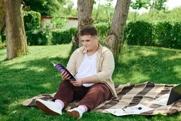 A unique person relaxes on a blanket, lost in a captivating book under the warm sun. — Stock Photo