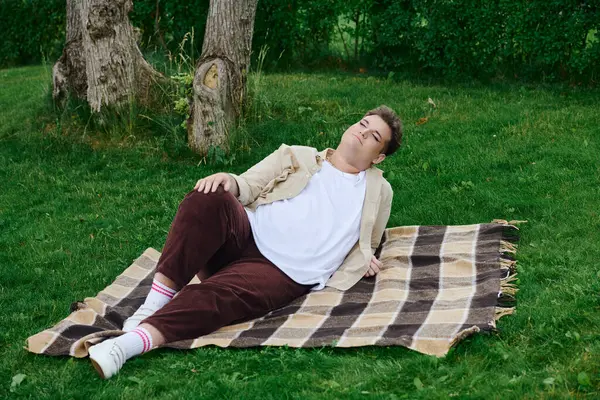A unique individual enjoys a peaceful moment on a checkered blanket surrounded by nature. — Stock Photo