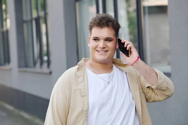 A unique person is smiling and holding a phone, talking happily in a city street ambiance. — Stock Photo