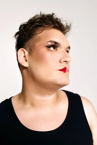 A queer person with dramatic makeup and striking eyelashes poses confidently, exuding charm. — Stock Photo