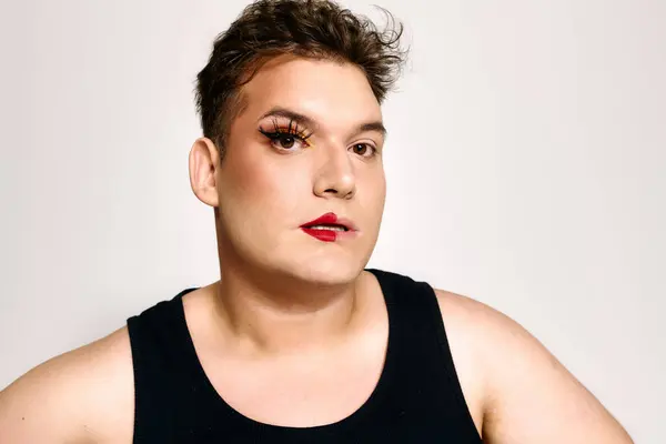 The portrait highlights a unique queer individual with bold makeup, showcasing confidence. — Stock Photo
