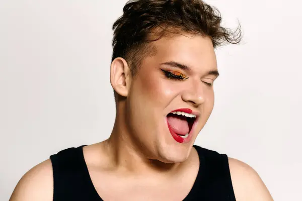 Dieses fesselnde Porträt zeigt eine queere Person, die ihr Glück mit kreativem Make-up ausdrückt. — Stockfoto