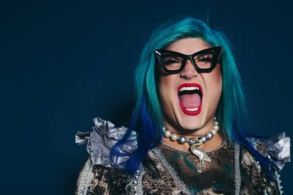 A vibrant queer person with colorful hair joyfully celebrates against a dark backdrop. — Stock Photo