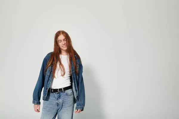 Un adolescente con i capelli rossi vibranti posa gioiosamente in un elegante ensemble di denim in uno studio. — Foto stock