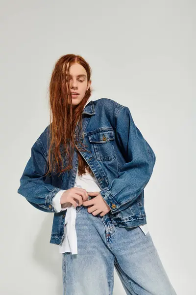 A teenage boy showcases his style in a denim outfit, exuding confidence in a studio environment with neutral tones. — Stock Photo
