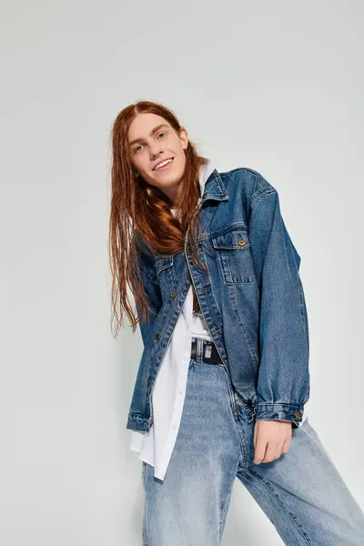 A teenage boy showcases his long red hair and denim style while posing in a contemporary studio environment. — Stock Photo