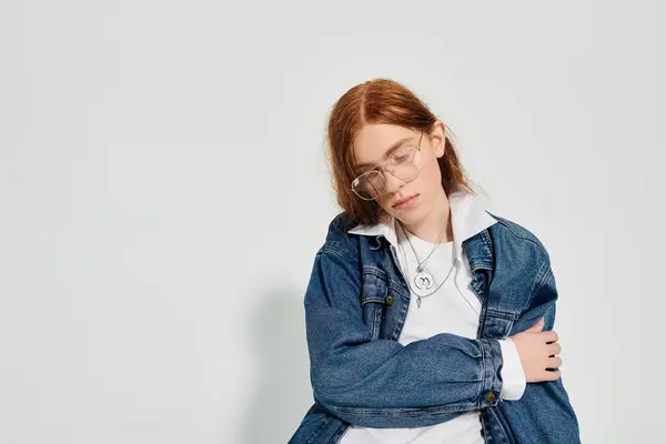 A young man with vivid red hair poses thoughtfully in a trendy denim ensemble, exuding casual elegance. — Stock Photo