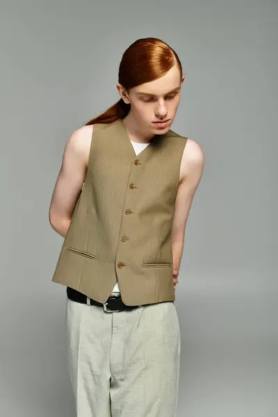 A teenage boy with striking red hair elegantly poses in a fashionable smart casual outfit against a grey backdrop. — Stock Photo