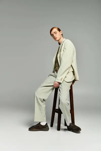 A teenage boy with striking red hair confidently poses in a chic smart casual outfit against a muted grey background. — Stock Photo