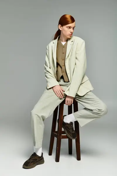 A young man with red hair showcases an elegant smart casual outfit in a minimalist grey backdrop. — Stock Photo