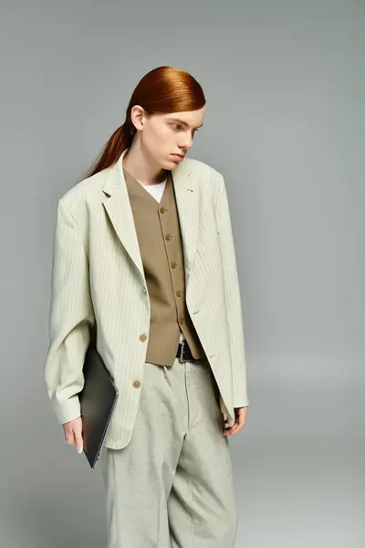 Ein Teenager mit auffallend roten Haaren präsentiert sich im smarten Casual-Look und verkörpert Eleganz in einer grauen Umgebung. — Stockfoto