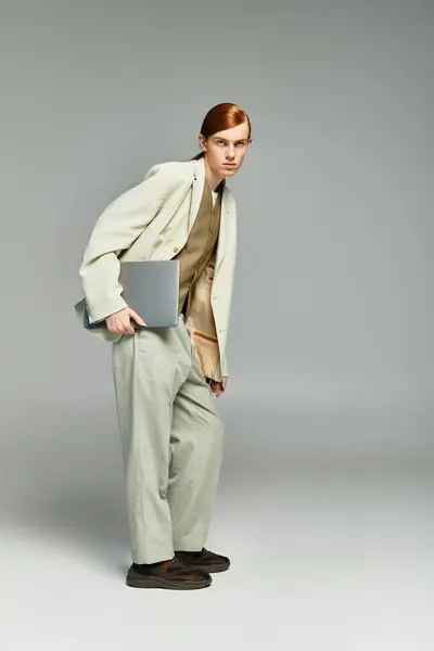 A stylish teenage boy with red hair poses confidently in a smart casual outfit against a grey backdrop. — Stock Photo