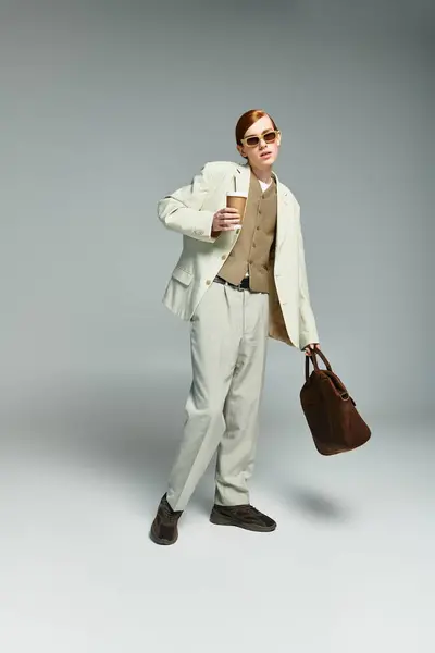 A teenage boy with striking red hair stands confidently in smart casual attire, holding a drink and a bag. — Stock Photo