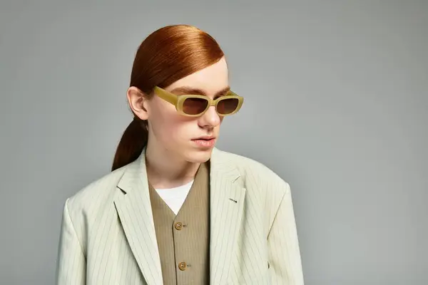 A teenage boy with striking red hair confidently poses in a chic smart casual ensemble in a sleek studio. — Stock Photo