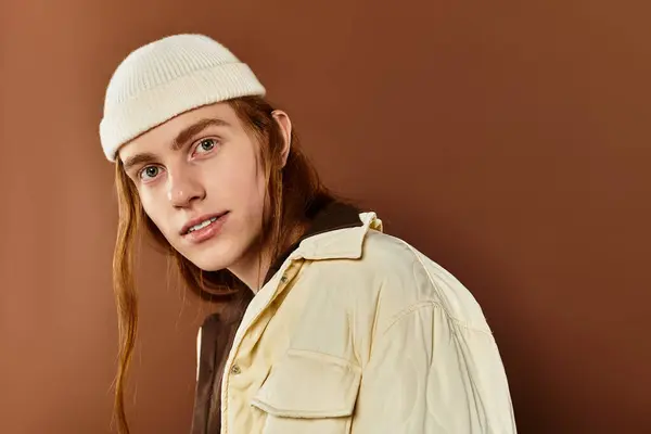 A young man with striking red hair poses confidently in fashionable attire against a warm backdrop. — Stock Photo