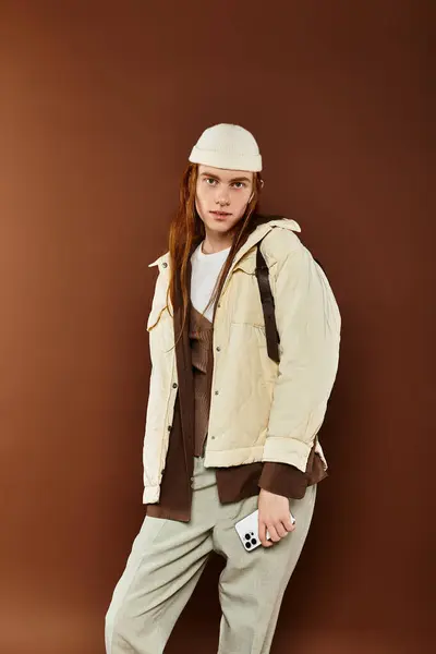 A confident teenage boy with red hair showcases his stylish outfit in a warm studio ambiance. — Stock Photo