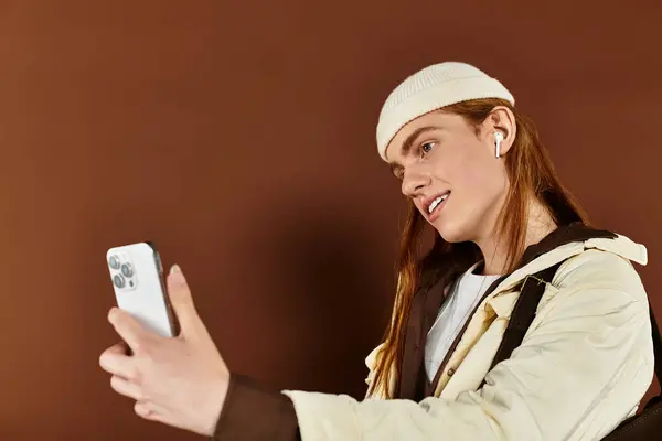 A trendy teenage boy with vibrant red hair poses confidently while capturing a selfie in the studio. — Stock Photo
