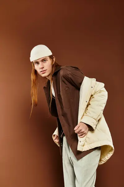 A teenage boy with striking red hair poses confidently in stylish attire against a warm background. — Stock Photo