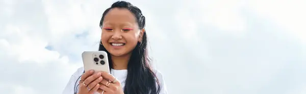 Ein stilvolles junges asiatisches Mädchen umarmt die Jugendkultur und lächelt breit, während sie sich mit Freunden im Freien trifft. — Stockfoto
