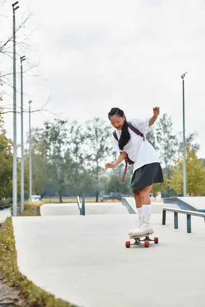 Exploring her passion for skateboarding, a stylish student girl rides confidently in an outdoor park. — Stock Photo