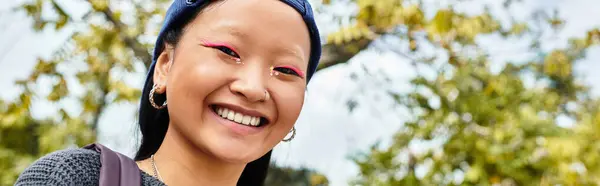 Uma jovem estudante asiática alegre desfruta de um belo dia lá fora, mostrando seu estilo vibrante e confiança. — Fotografia de Stock