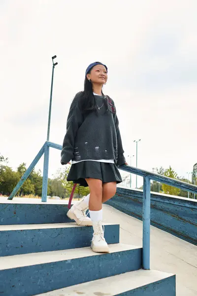 A stylish young Asian girl walks confidently down skate park steps, embracing youth culture. — Stock Photo