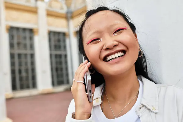 A stylish young woman smiles brightly while talking on her phone, enjoying university life and campus diversity. — Stock Photo