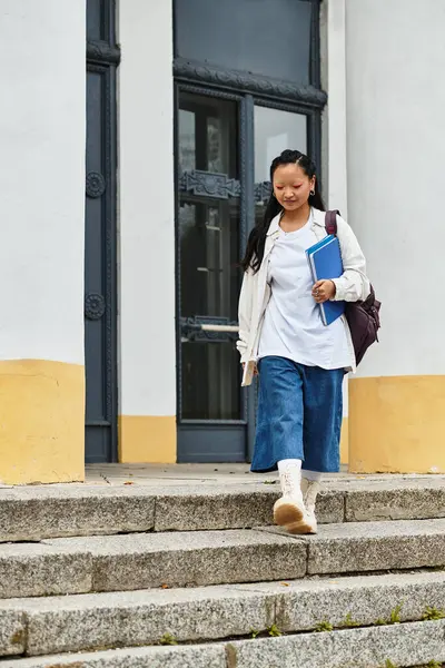 A young woman in trendy attire descends the university steps, radiating confidence and capturing youth culture. — Stock Photo