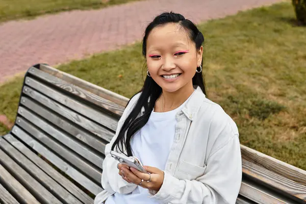 A stylish young student relaxes on a bench, engaging with friends while embracing vibrant campus culture. — Stock Photo