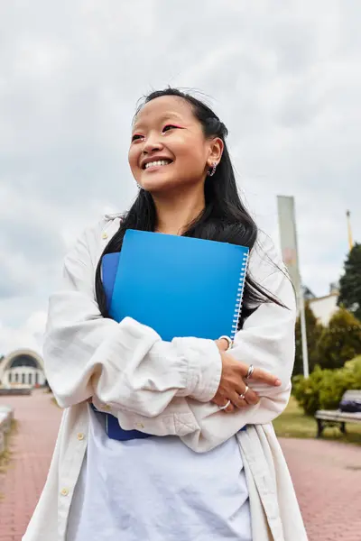 A cheerful young woman enjoys her time near a university, embracing diversity and youth culture. — Stock Photo