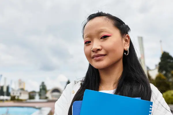 Uma jovem elegante posa com confiança com seus cadernos, abraçando a cultura e a diversidade do campus. — Fotografia de Stock